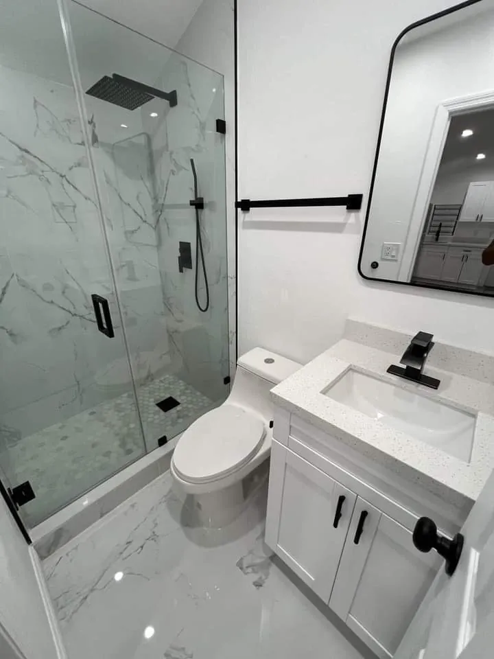 A bathroom we finished: a glass shower with marble-look tile, black fixtures and a white vanity