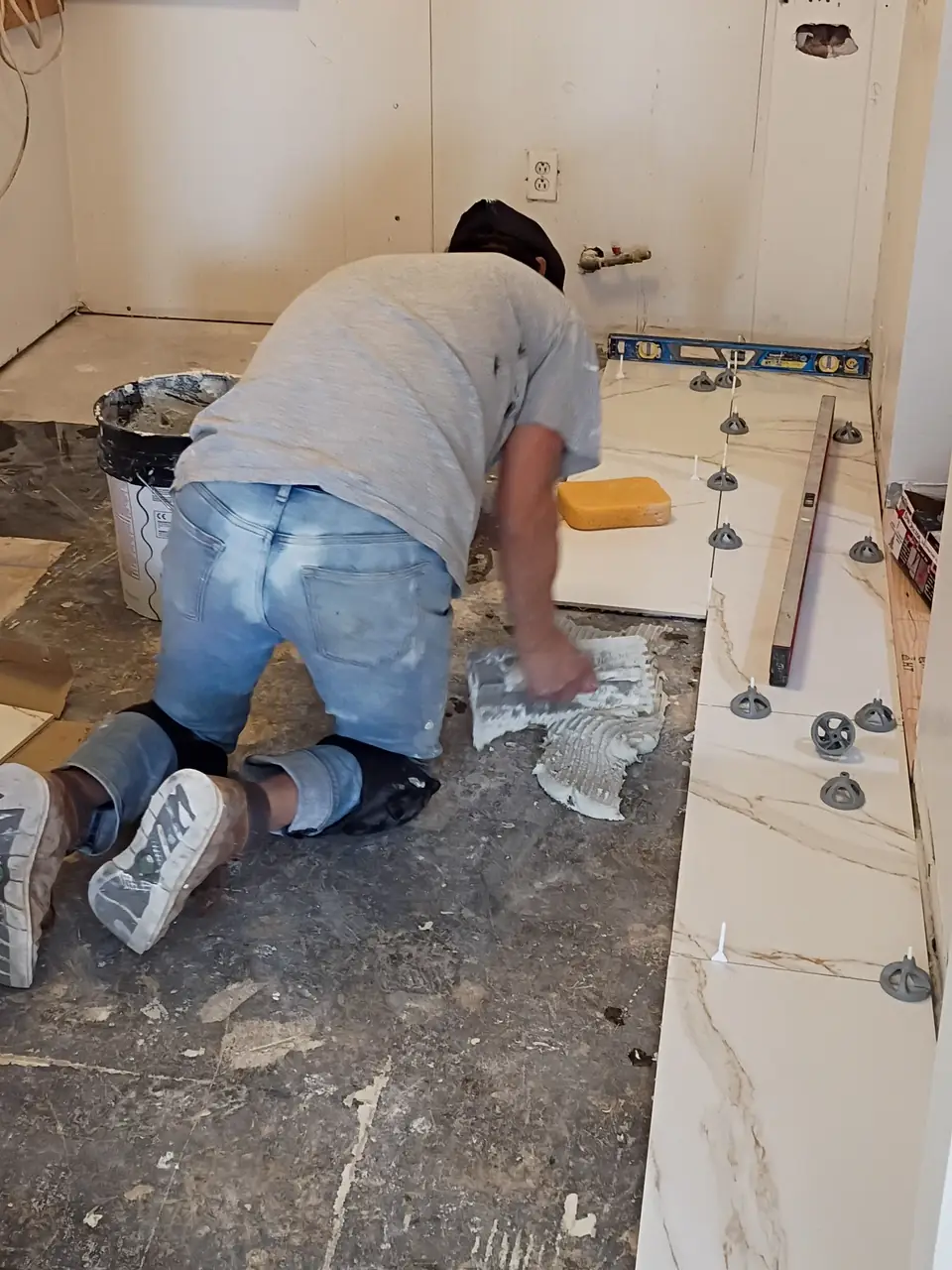 One of our crew setting large marble-look floor tiles with levelling clips