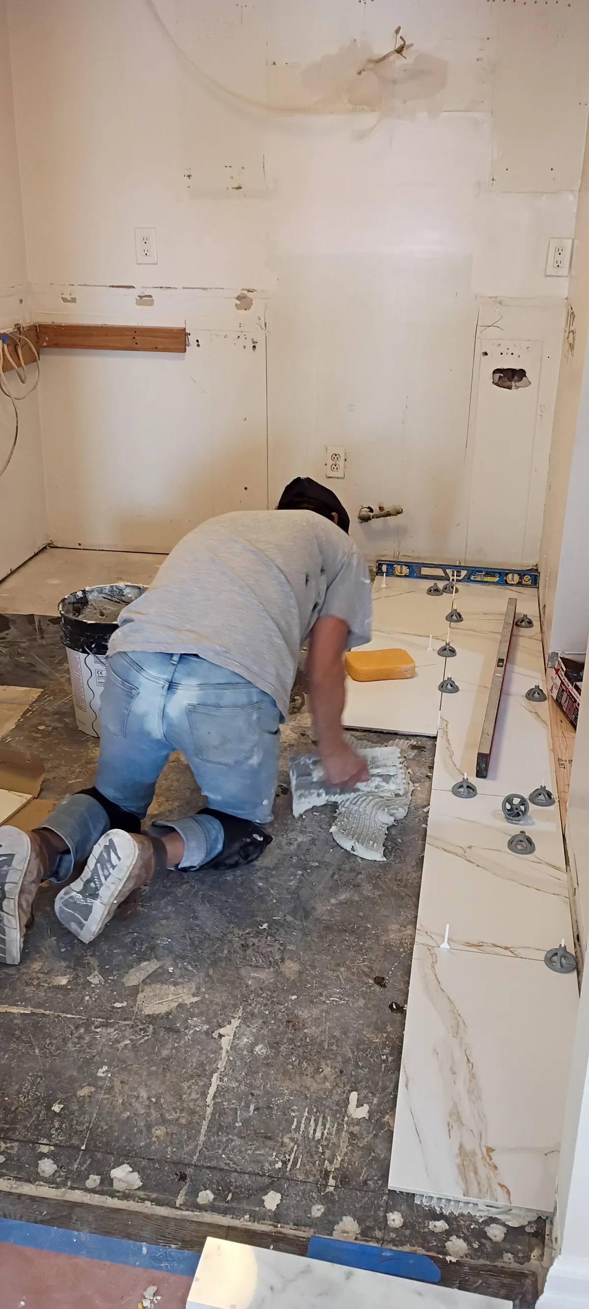 One of our crew setting large marble-look floor tiles with levelling clips